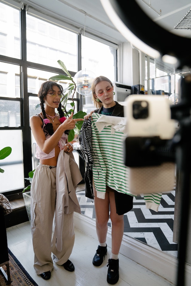 a couple of young lady instagram influencers recording an instagram reel where they are promoting a clothing line