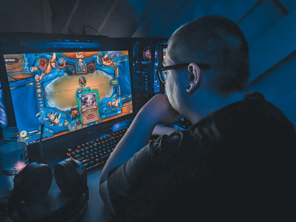 Young man playing video games on his computer in a dark room