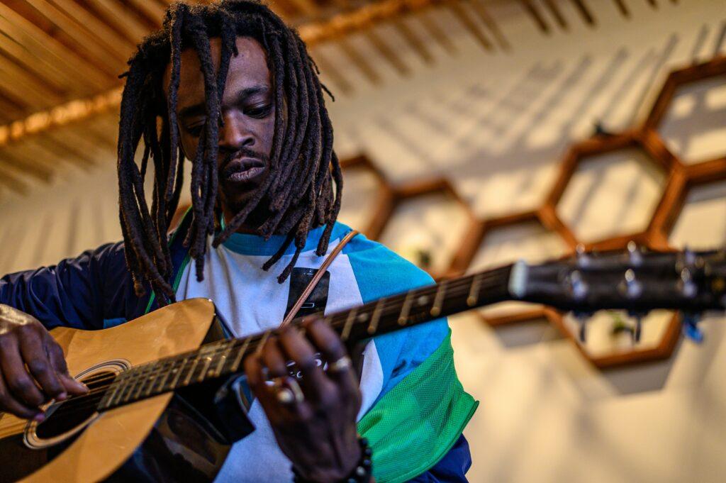 Man with dreads playing music with his guitar