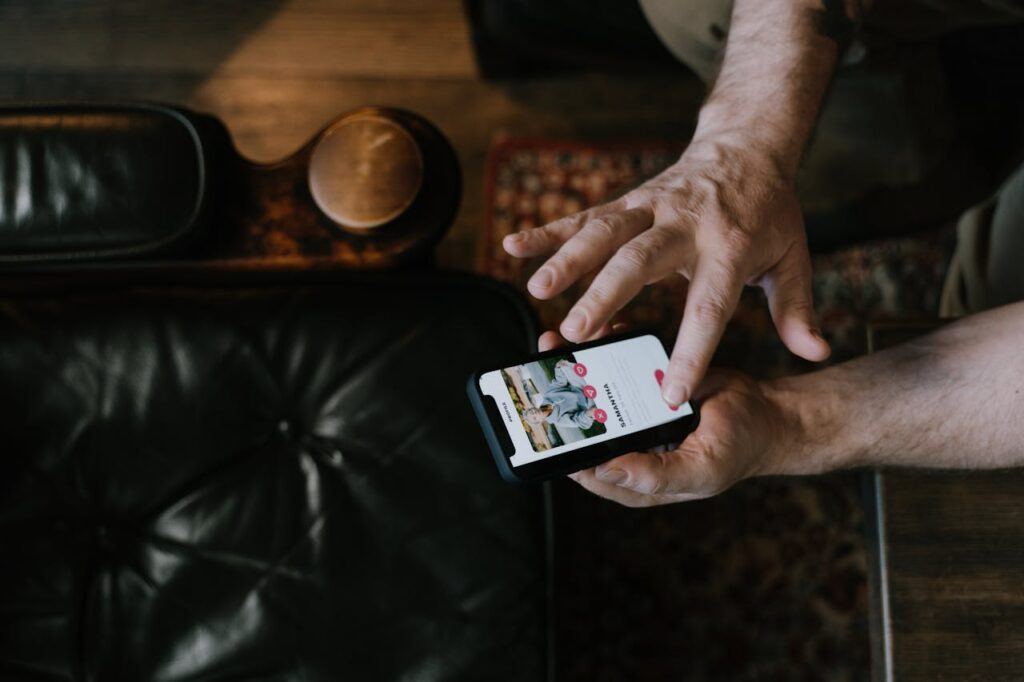 picture of someones hands holding a phone and swiping through a dating app