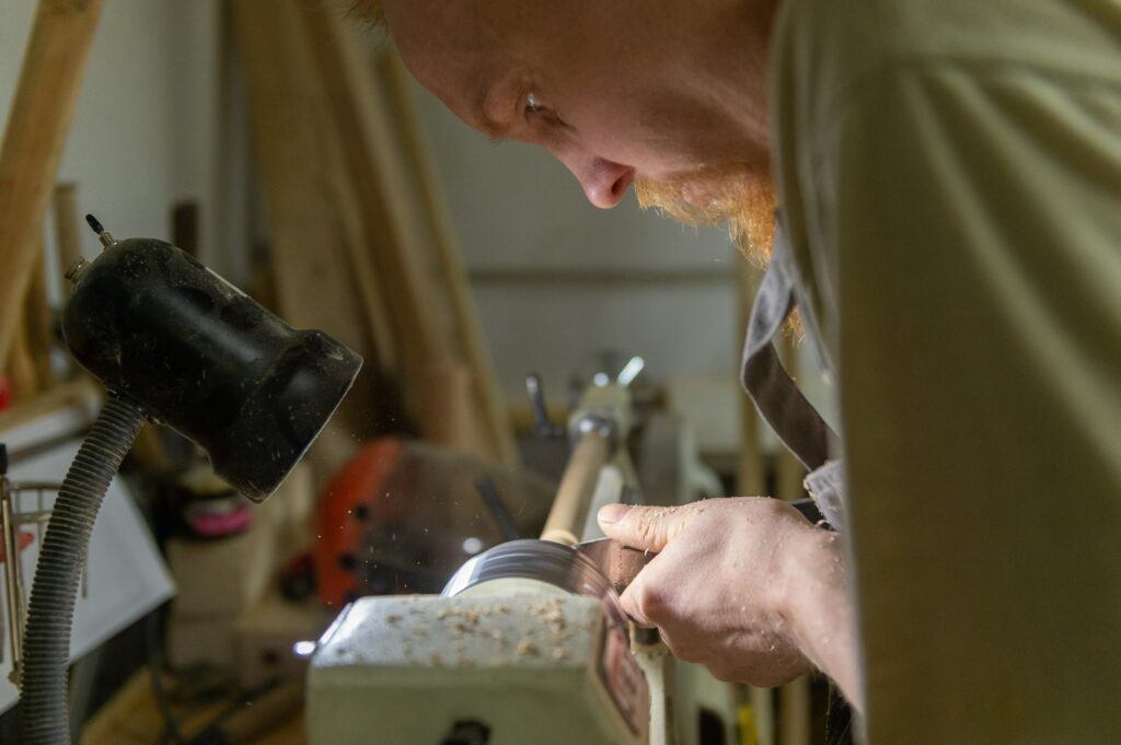 woodworking with a man turning a woodworking project on a lathe.